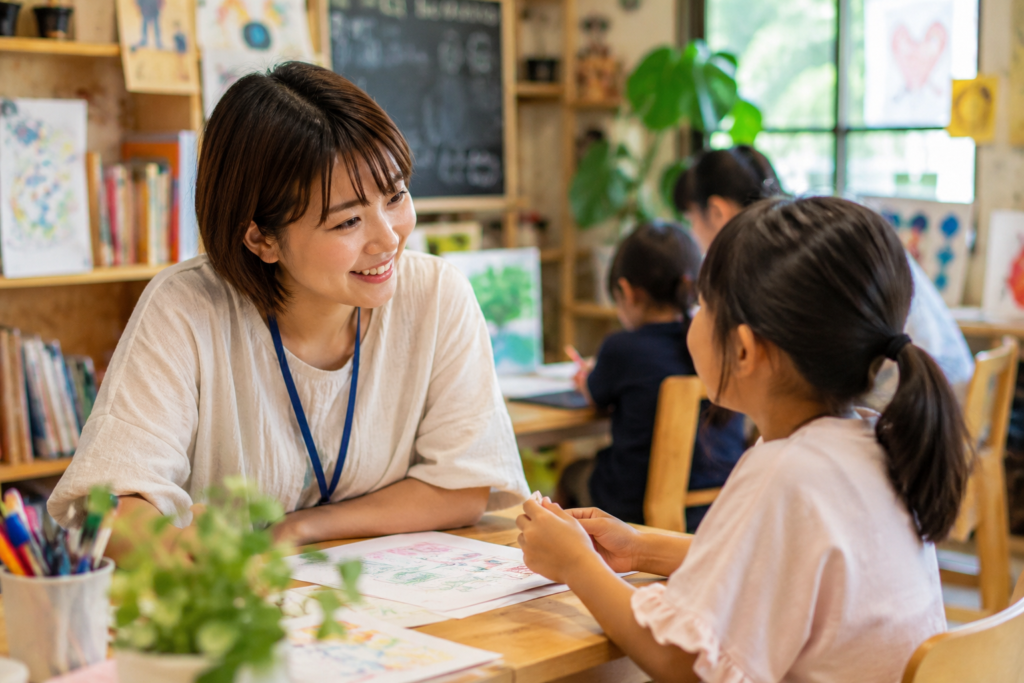 フリースクールの先生が、子どもの作品を見ながら一対一で話を聞き、気持ちに寄り添っている様子