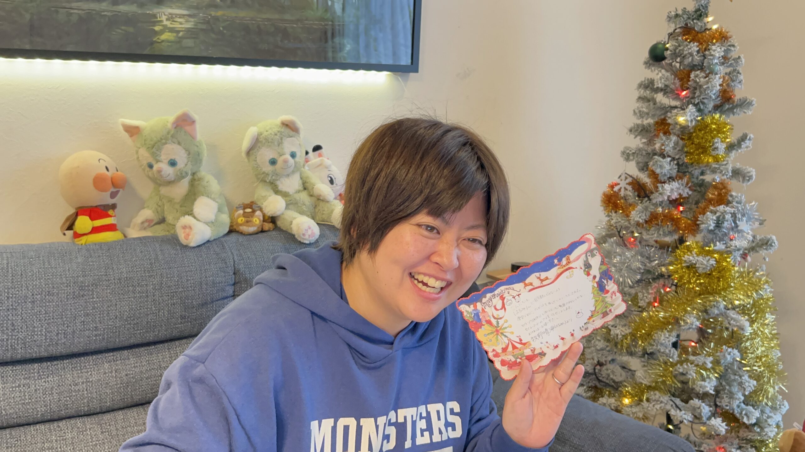 手作りのメッセージカードを手に、笑顔を見せる佐藤さん